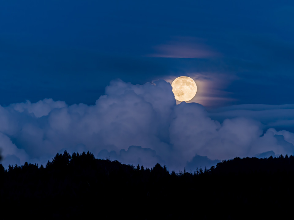 Lever de pleine lune derrière les nuages 