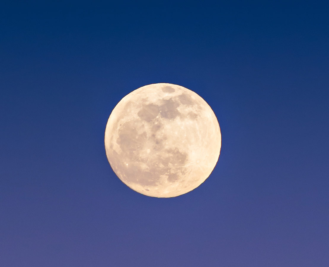 La pleine lune se lève dans les lueurs du crépuscule