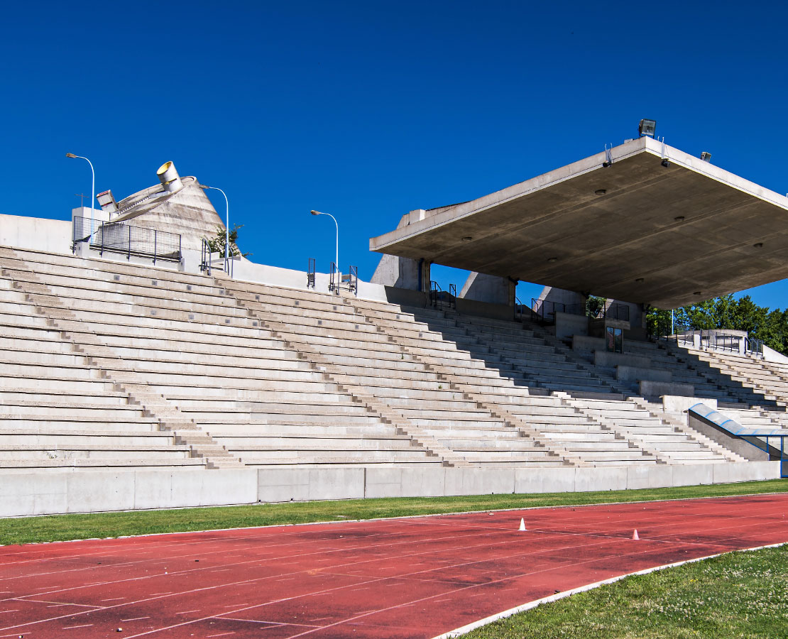 Piste d'athlétisme et gradins du stade Le Corbusier devant l'église Saint-Pierre à Firminy-Vert